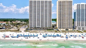 A beachfront hotel with multiple high-rise buildings, a sandy beach, and numerous umbrellas.