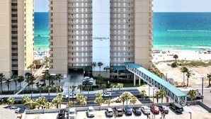 A high-rise hotel with a central entrance, multiple floors, and a view of the beach and ocean.