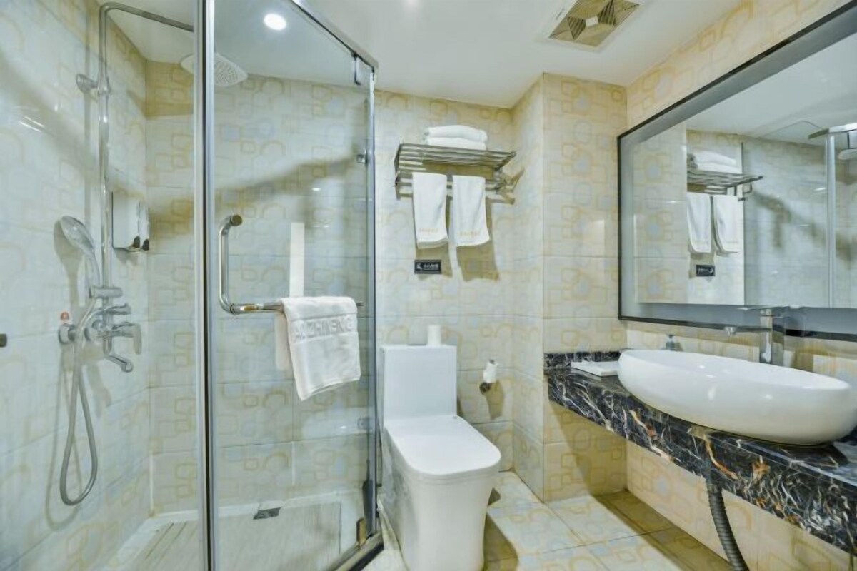 A modern bathroom with a glass shower enclosure, a white toilet, and a large sink with a marble countertop.