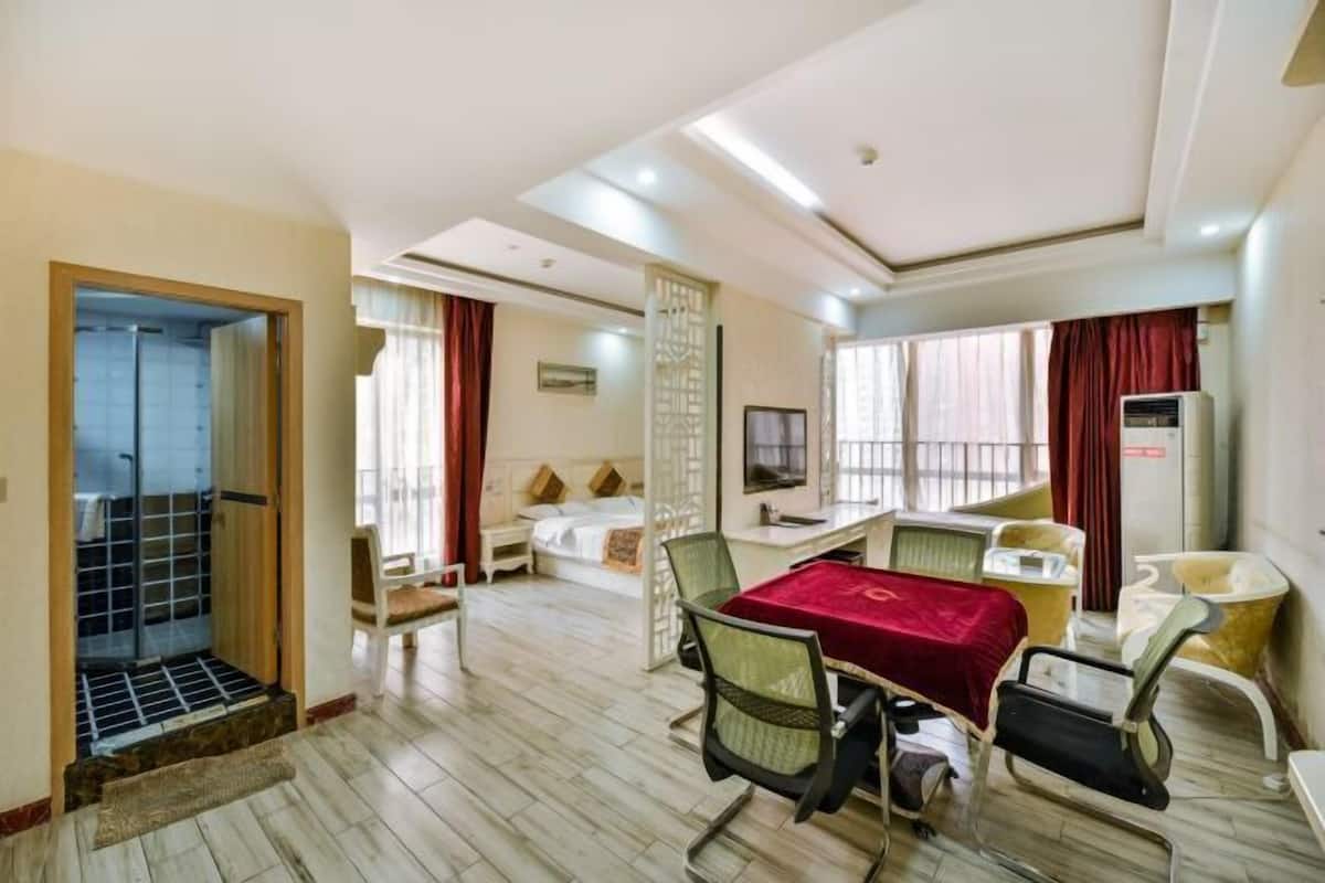 Ein Hotelzimmer mit Bett, Schreibtisch, Stuhl, Fernseher und einem Badezimmer mit Dusche und Toilette.