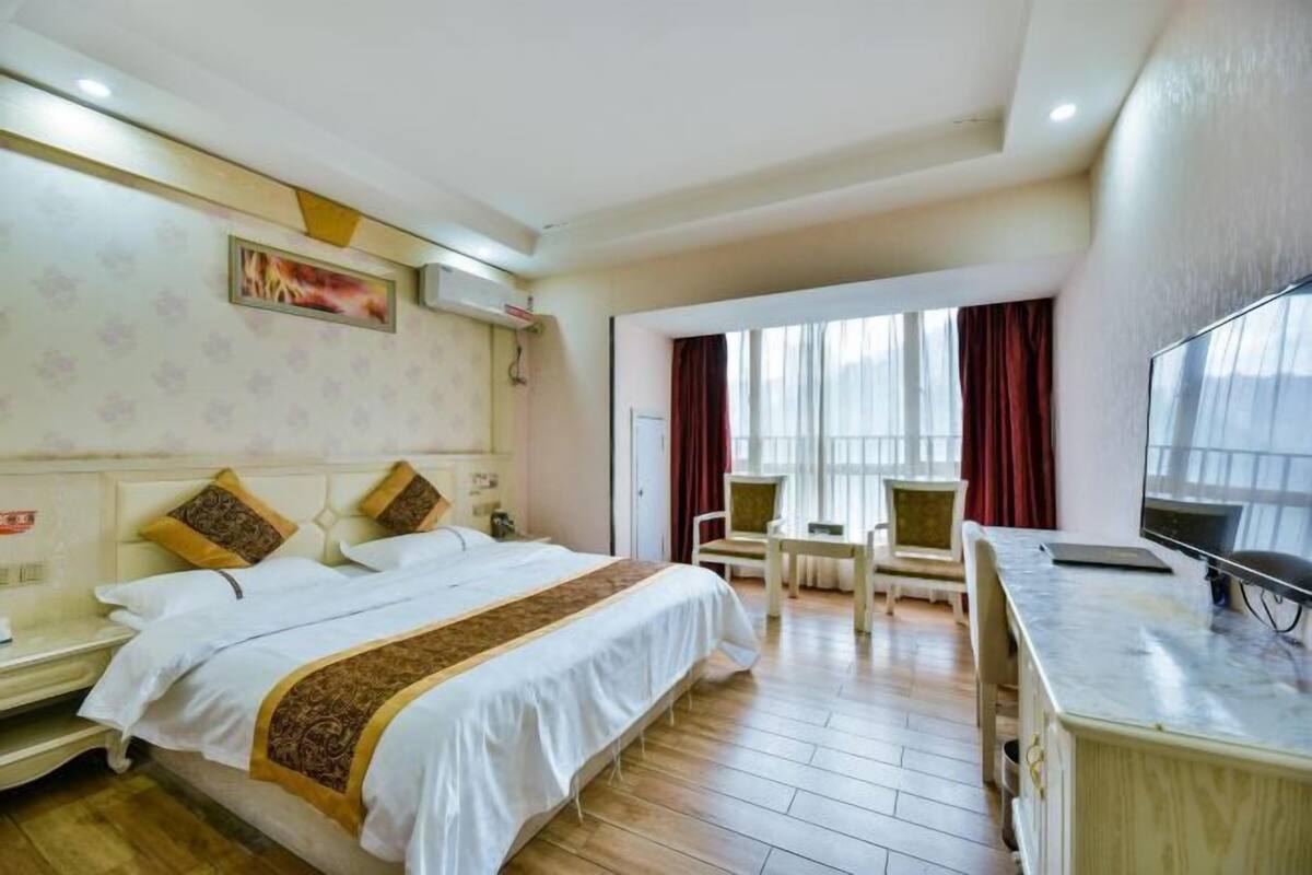 Ein Hotelzimmer mit einem großen Bett, einem Schreibtisch, einem Sessel und einem Fernseher.