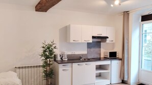 Eine moderne Küche mit weißen Schränken, einem eingebauten Herd und einem Fenster mit Vorhängen.