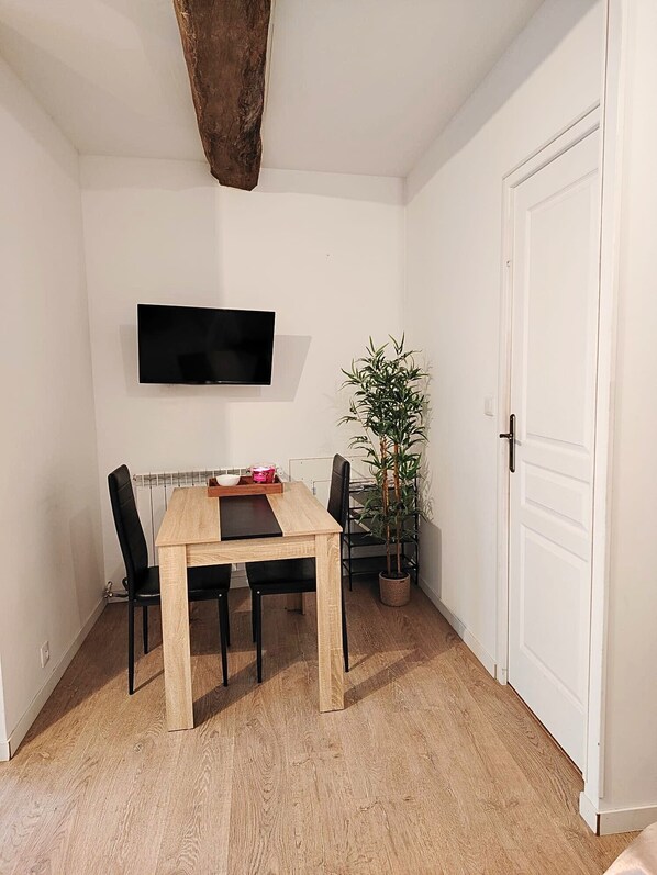 A dining area with a wooden table, black chairs, a potted plant, and a white door.