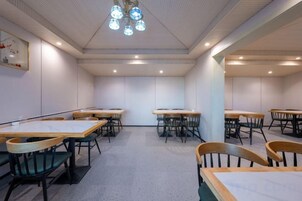 A dining area with tables and chairs, a ceiling light fixture, and a wall-mounted picture.