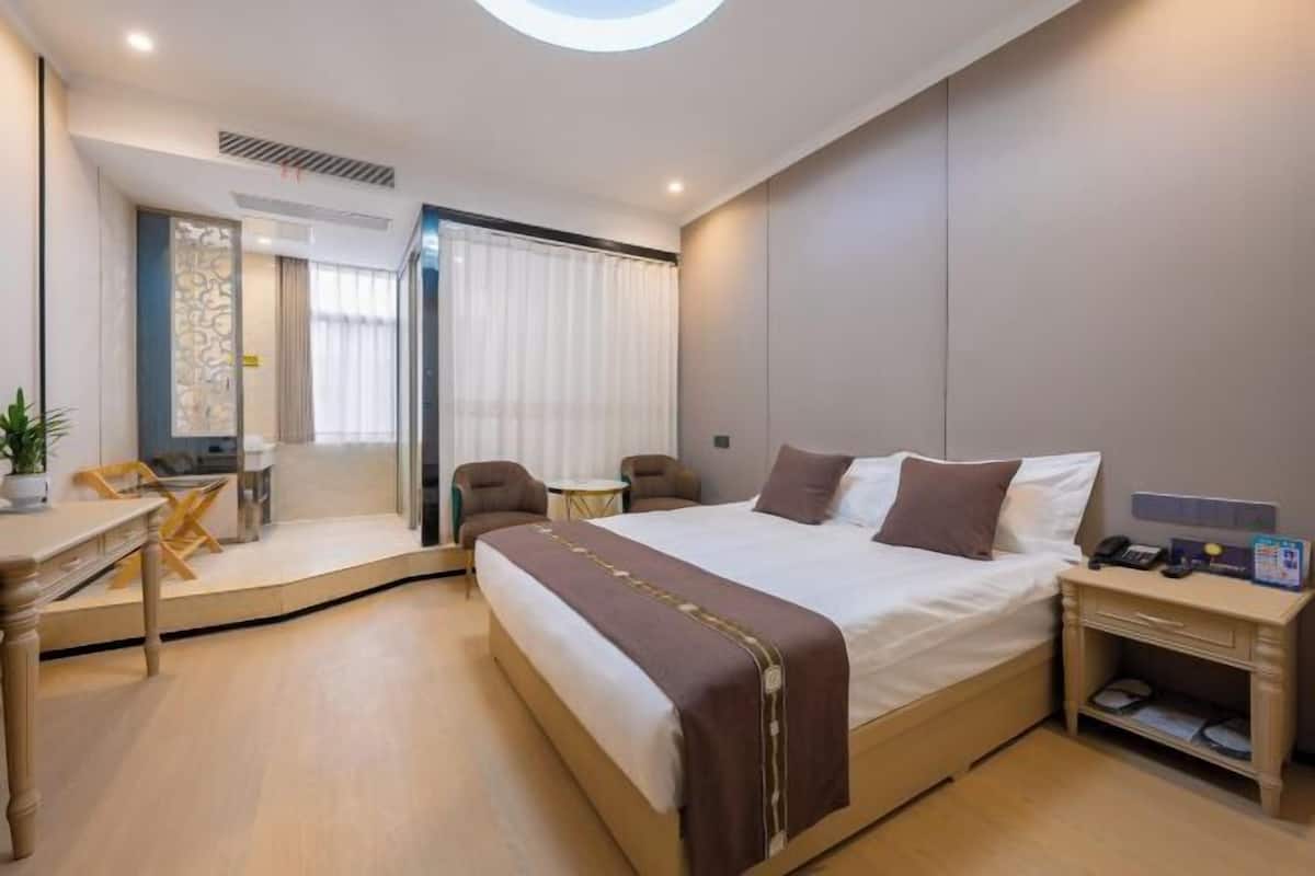 A modern hotel room with a large bed, a desk, and a chair.