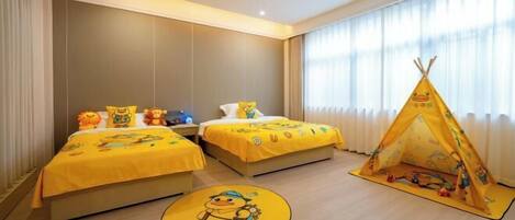 A hotel room with two beds, a yellow play tent, and a round rug with a duck design.