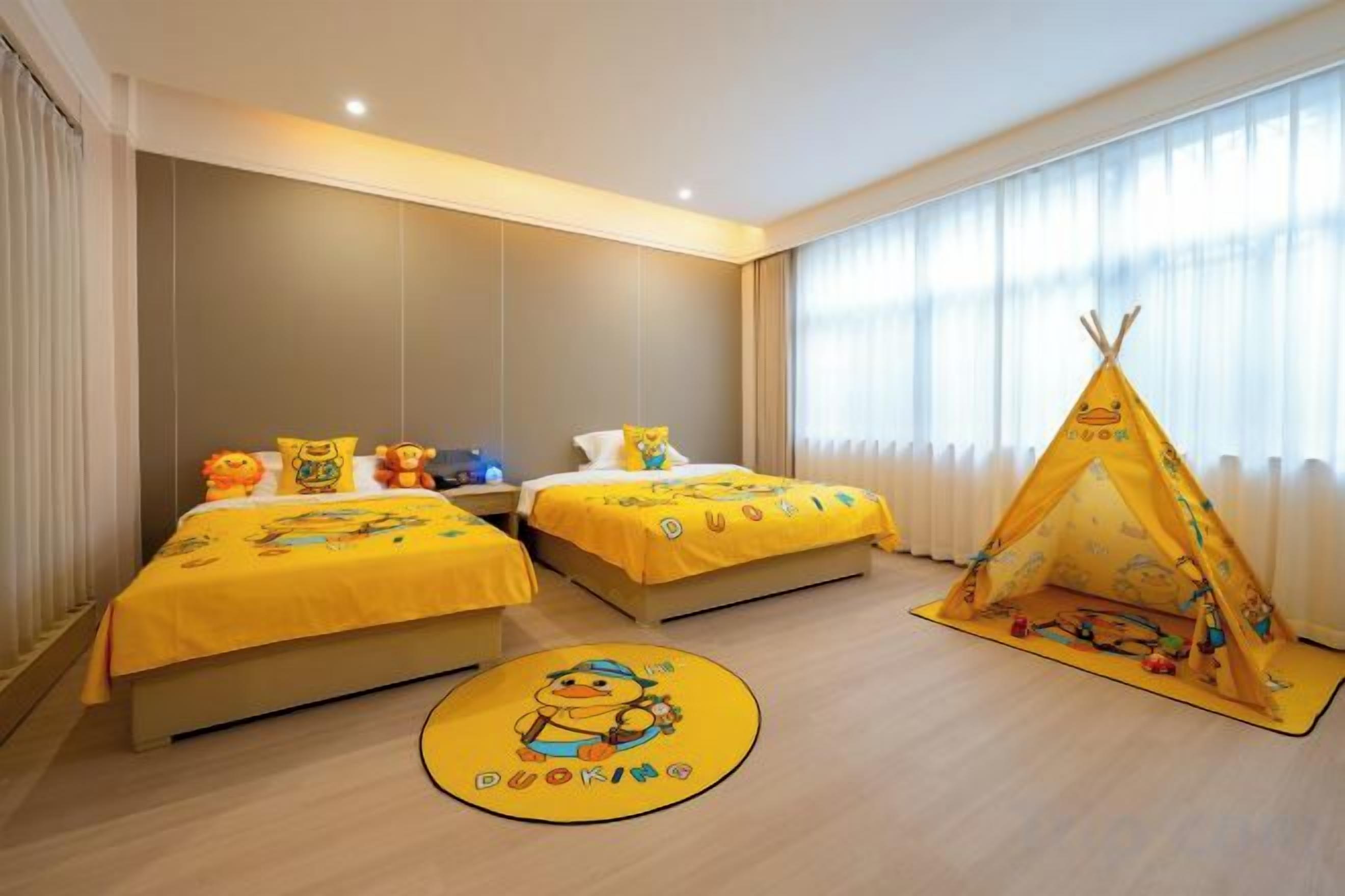 A hotel room with two beds, a teepee, and a circular rug with cartoon characters.