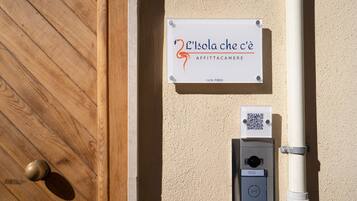 Een houten deur, een bord met een QR-code en een stroomkast op een beige muur.