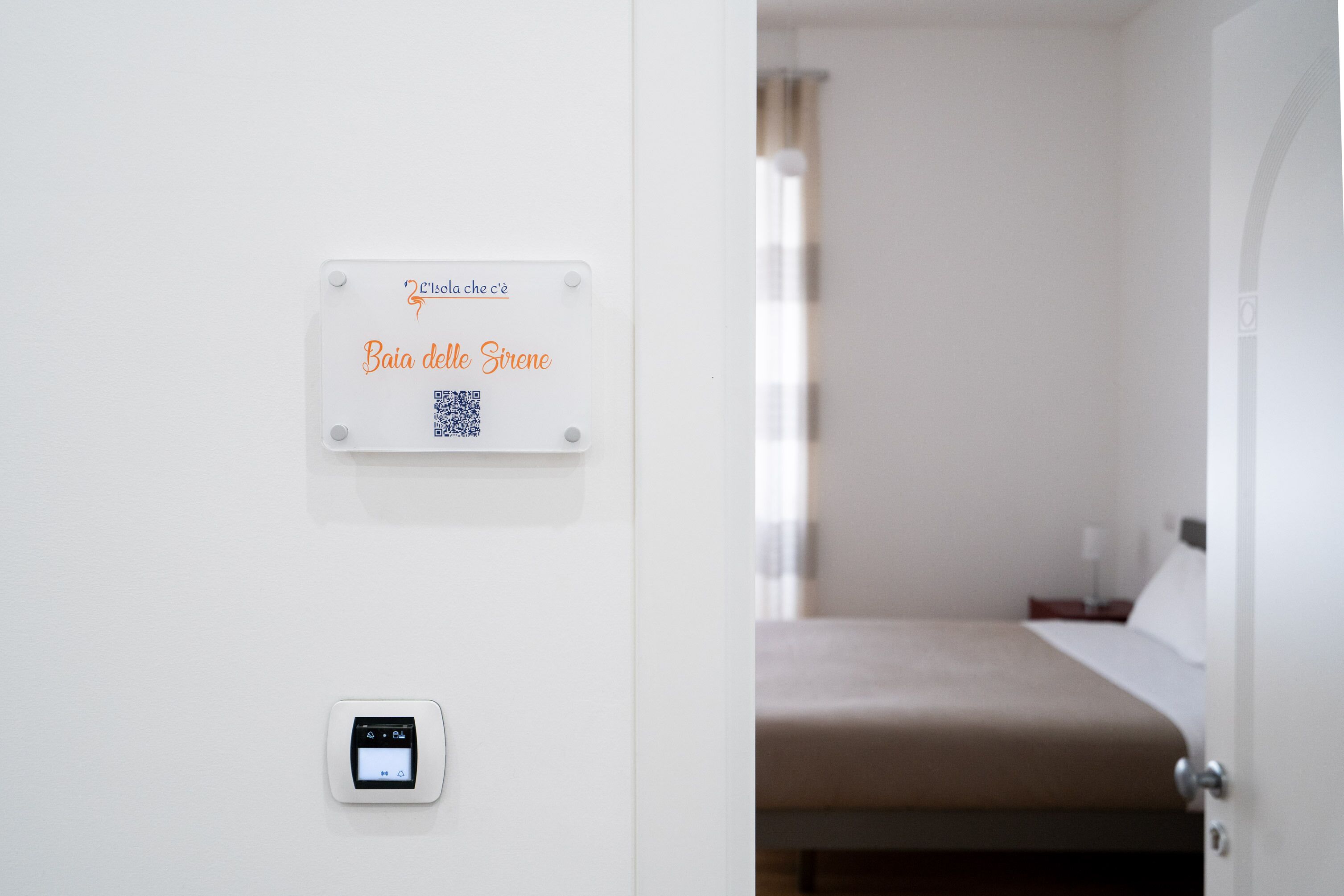 Una habitación de hotel con una cama, un termostato y un cartel en la pared.