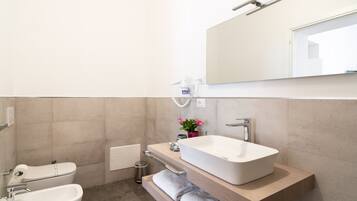 A modern bathroom with a large rectangular sink, a toilet, and a bidet.