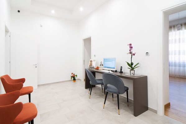 A modern office with a desk, computer, chairs, and a potted plant. - L'isola che c'è (Cagliari)