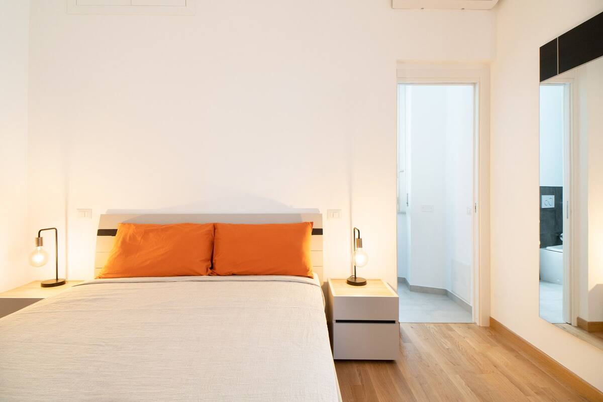 A bedroom with a bed, two bedside tables, and a nightstand.