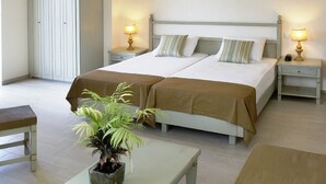 A double bed with two nightstands, a bedside table, a potted plant, and a wardrobe. - Almyrida Beach Hotel (Apokoronas)