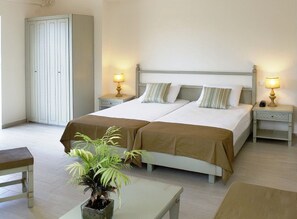 A double bed with two nightstands, a bedside table, a potted plant, and a wardrobe. - Almyrida Beach Hotel (Apokoronas)