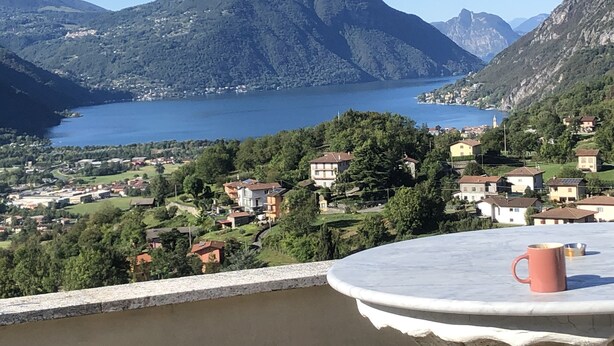 A terrace with a table and a mug, overlooking a lake and a village with houses and mountains in the background. - Penthaus am Luganersee - Comer See (Carlazzo)