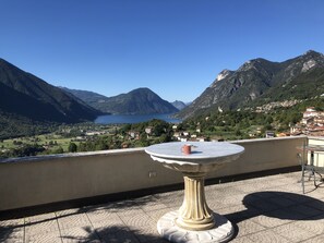 Una terraza con una mesa y vistas a un lago y montañas.