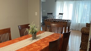 A dining area with a table set for six, wooden chairs, a lace table runner, and a vase with flowers.