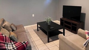 A living room with a sofa, a coffee table, a TV, and a small plant.
