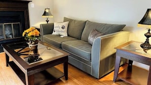 A living room with a sofa, two coffee tables, a fireplace, and lamps.