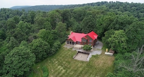 An aerial view of a house with a red roof surrounded by dense forest. - Texter Mountain Lodge - 105 Acre Mountain Home (Reinholds)