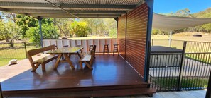 An outdoor patio with wooden furniture, including a table and benches, under a shaded area with a view of the surrounding landscape. - Roo Or 2 on Streeter (Agnes Water)