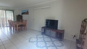 A living room with a dining area, a television on a stand, and a patterned rug.