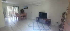 A living room with a dining area, a television on a stand, and a patterned rug.