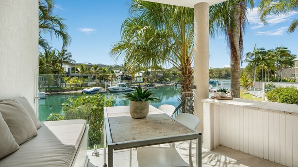 Ein Balkon mit Blick auf einen Yachthafen, einem Tisch mit einer Pflanze und einem Sofa.