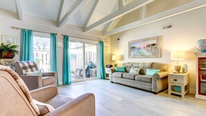 A spacious living room with a high ceiling, a sofa, a chair, and a dining area with a table and chairs. - Community Perks! Sunny Hilton Head Island Retreat (Hilton Head Island)