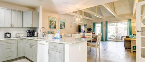 A spacious kitchen with a central island, a dining area with a view, and a living space with a large window.