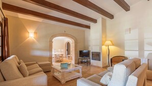 Un salon avec une cheminée, un téléviseur et un coin repas comprenant des chaises et une table.