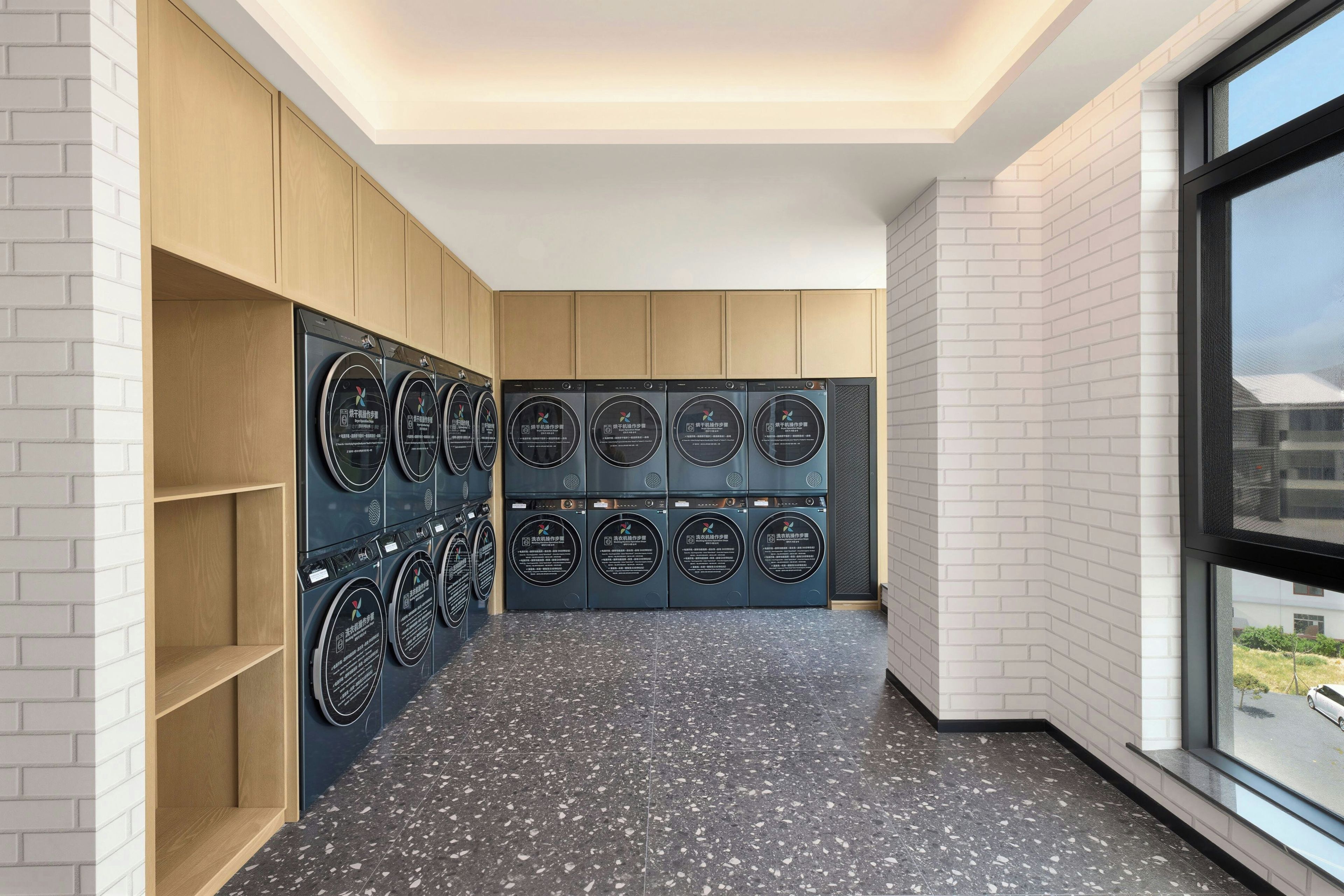 Un cuarto de lavandería con varias lavadoras, armarios de madera y un piso de baldosas con vetas.