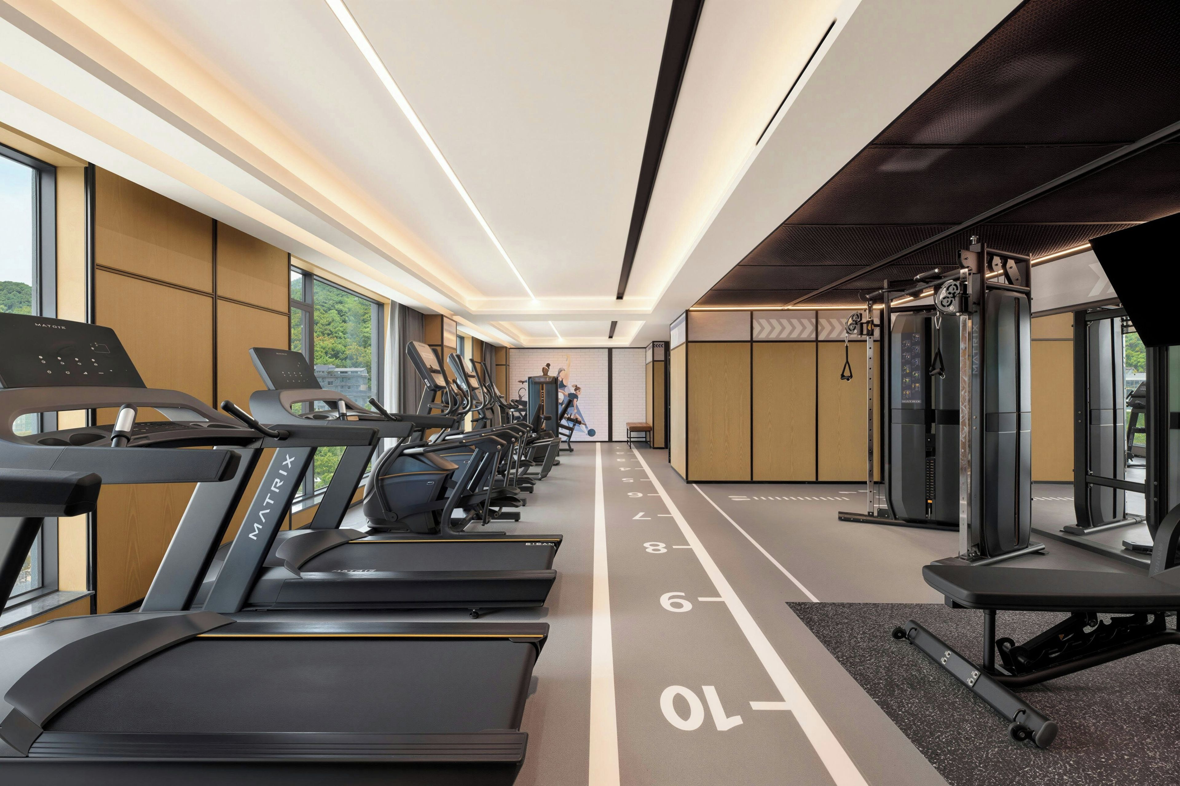 Un gimnasio con cintas de correr, máquinas de pesas y una pared con equipo de ejercicio.