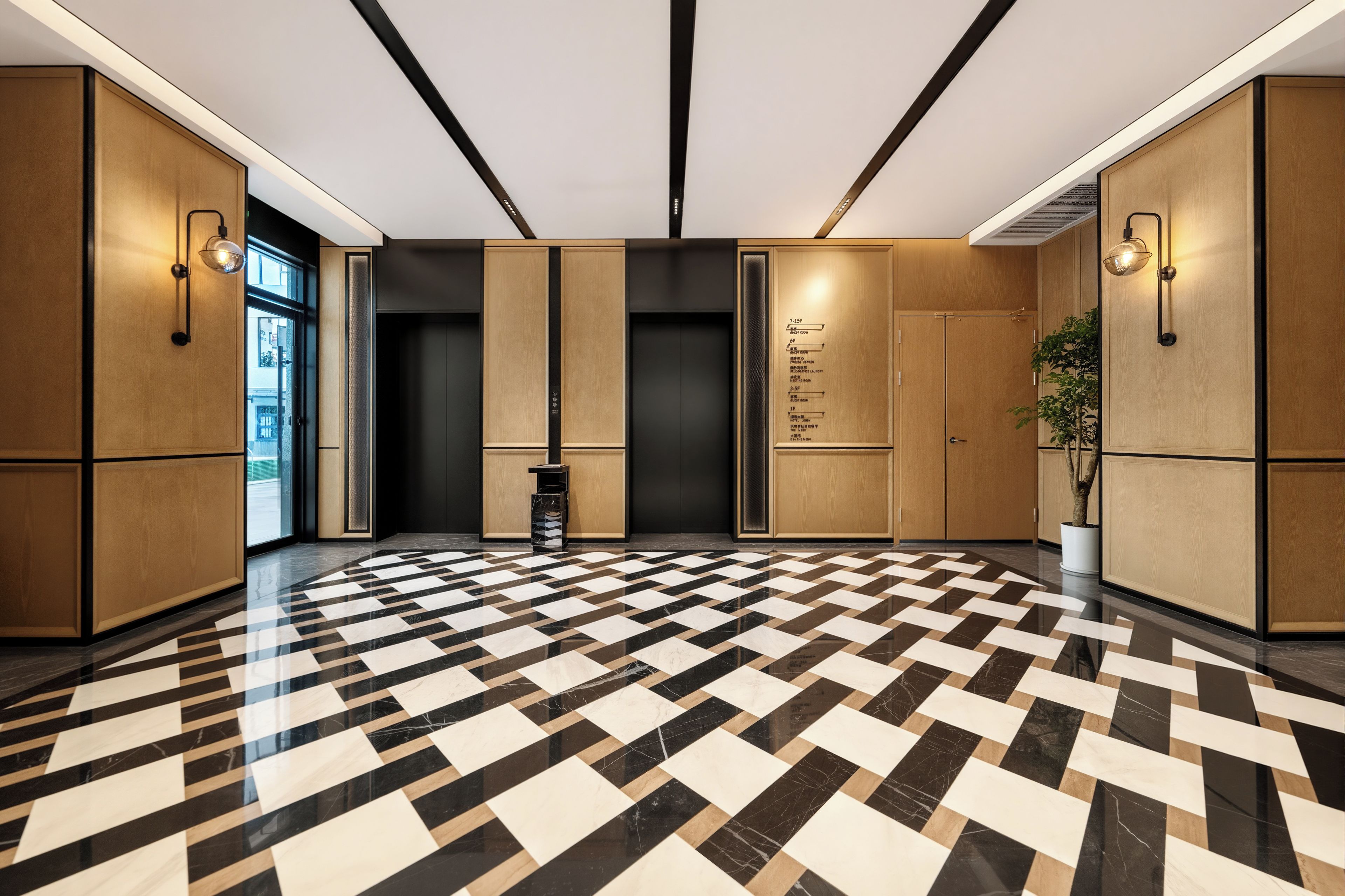 A hotel lobby with a checkered floor, wooden paneling, and a wall-mounted directory.