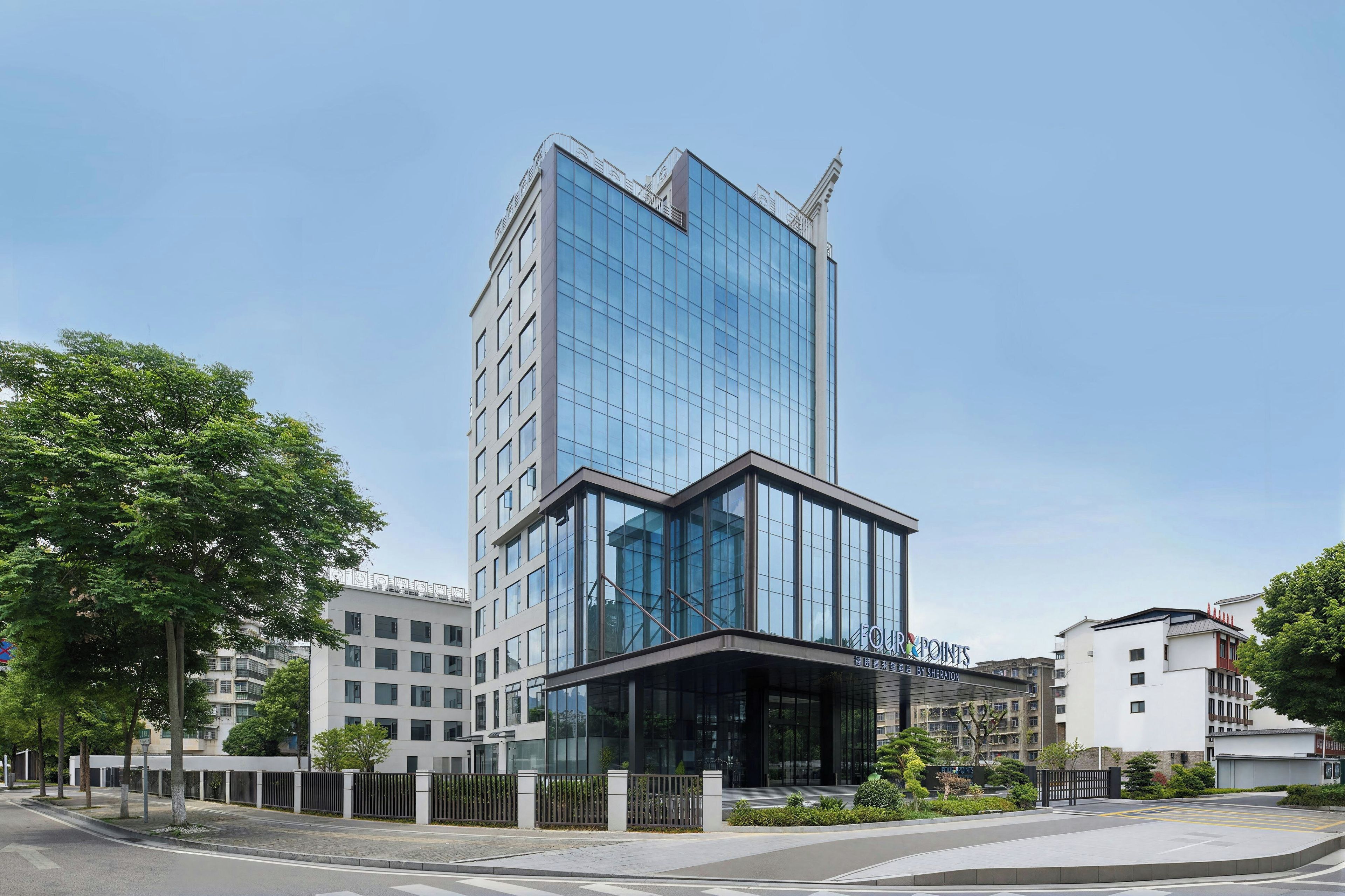 A modern hotel building with a glass facade, multiple floors, and a prominent entrance.