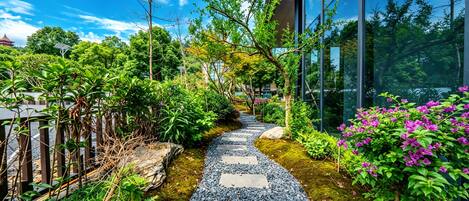 A pathway with stepping stones leading through a garden with various plants and trees.