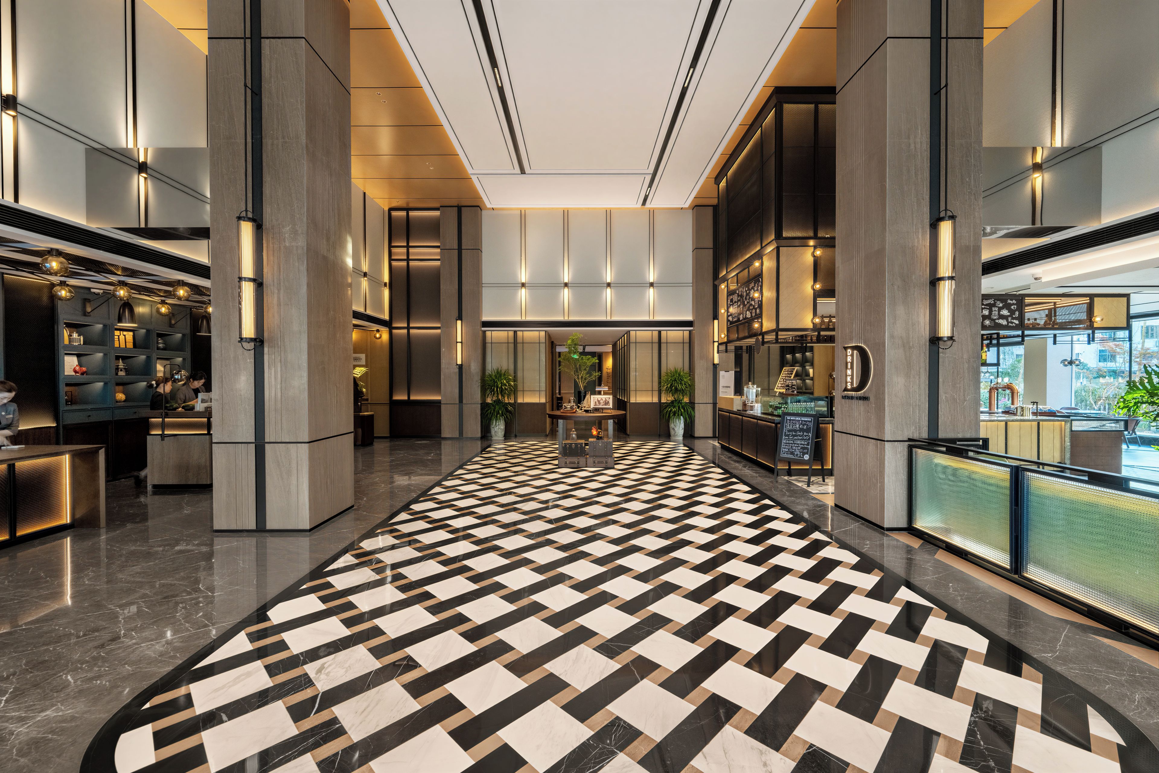 A modern hotel lobby with a checkered floor, a reception desk, and a bar area.