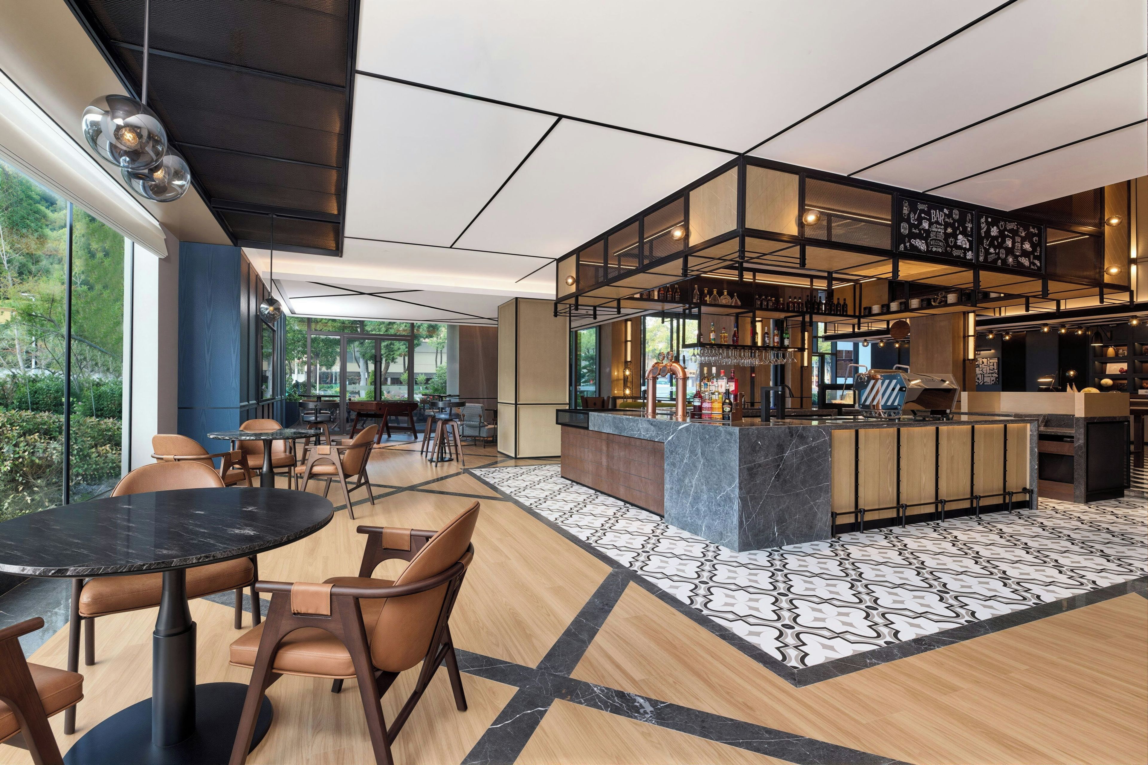 A modern bar area with a bar counter, seating, and a view of the outdoors.