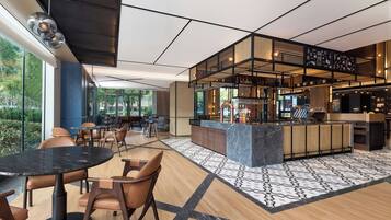 A modern bar area with a bar counter, seating, and a view of the outdoors.