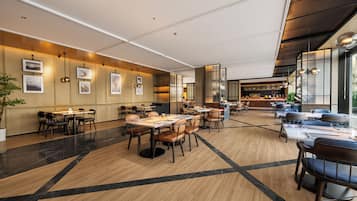 Un restaurante espacioso con techos altos, iluminación moderna y una variedad de disposiciones de asientos.