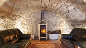 A cozy room with stone walls, a fireplace, two leather sofas, and a patterned rug. - Private villa for 20 guest, boutique hotel style! (Rubió)