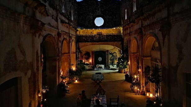 An outdoor dining area with tables and chairs, surrounded by arches and a large moon visible in the sky. - Breathtaking 18th Century Converted Convent! (Vila-Rodona)