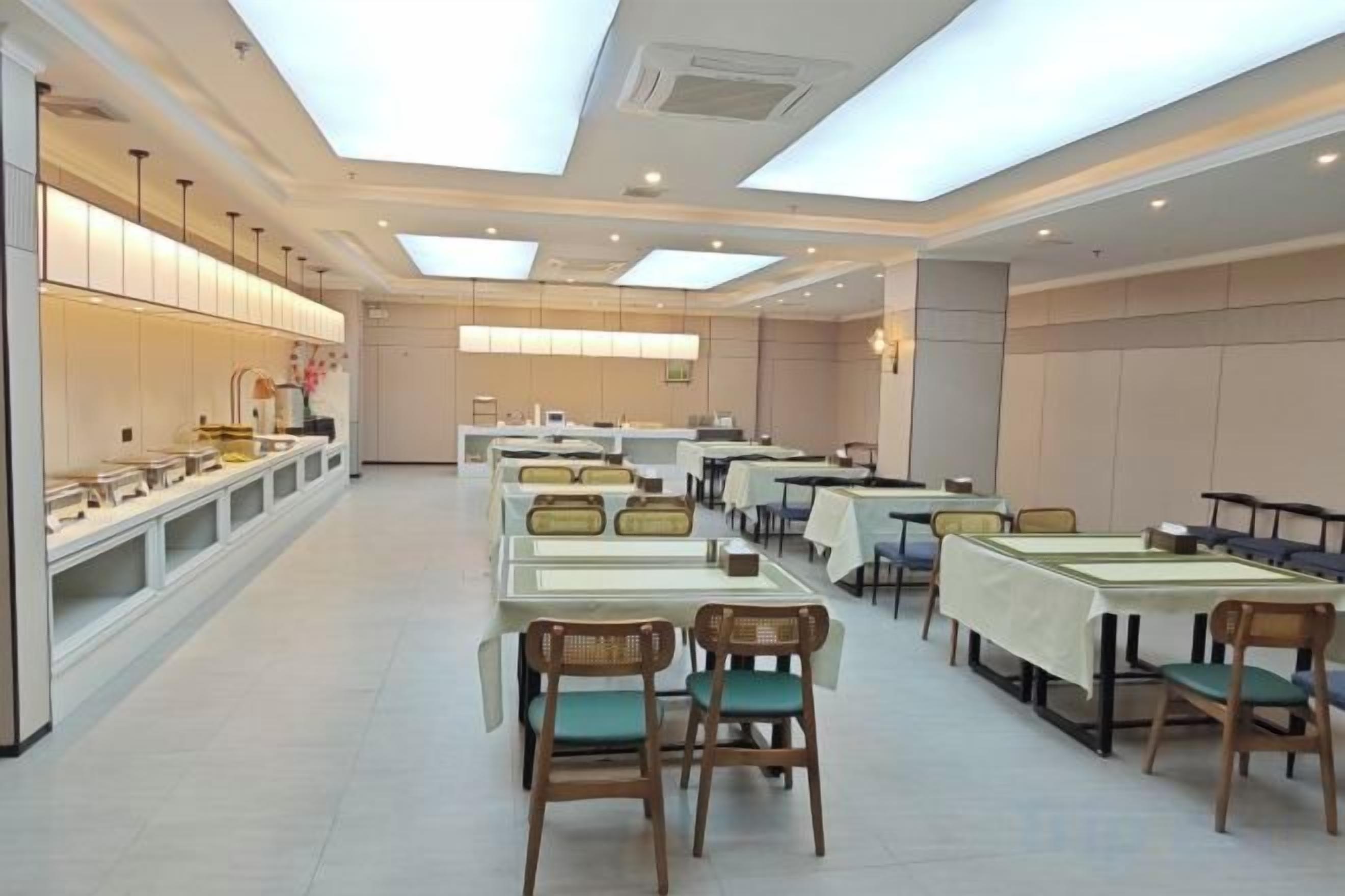 A spacious dining area with multiple tables and chairs, a long counter with display cases, and a modern ceiling design.