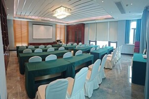 A conference room with rows of tables and chairs, a projector screen, and a large window.