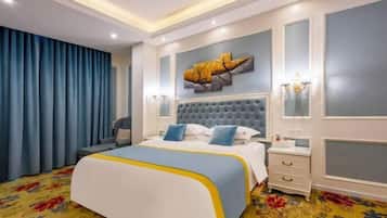 A hotel room with a large bed, a tufted headboard, a decorative wall piece, a nightstand, and a patterned carpet.