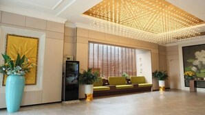 Un lobby moderno con una lámpara de techo, zona de estar y plantas decorativas.