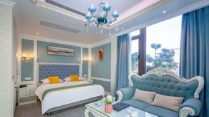 Un dormitorio con una cama, un sofá, una mesa de centro de cristal y una araña.