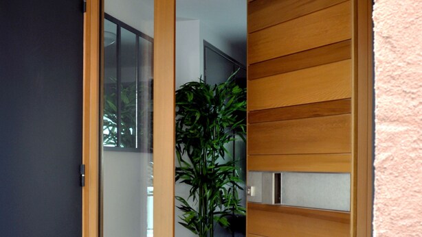 A modern entrance with a sliding glass door, a potted plant, and a textured wall. - Villa Ibanova 3: Studio, private parking (Collioure)