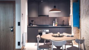 Une cuisine moderne avec un îlot central, des luminaires suspendus et une porte bleue.