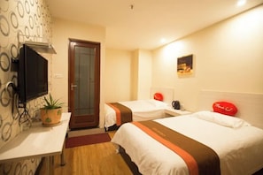 A hotel room with two beds, a TV, a small table, a potted plant, and a door. - Shushi Hotel (Shiyan)